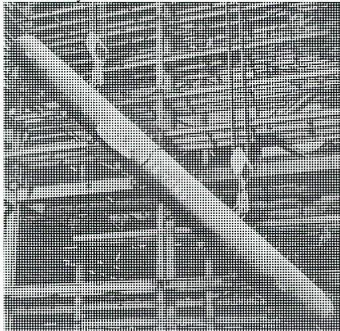 A black and white photograph showing a large, cylindrical boiler drum being hoisted by a crane. The drum is tilted at an angle, and its surface is covered in a dense, cross-hatched pattern. The background shows the structural steel framework of a building, with beams and columns visible. The lighting is bright, casting shadows on the drum and the surrounding structure.