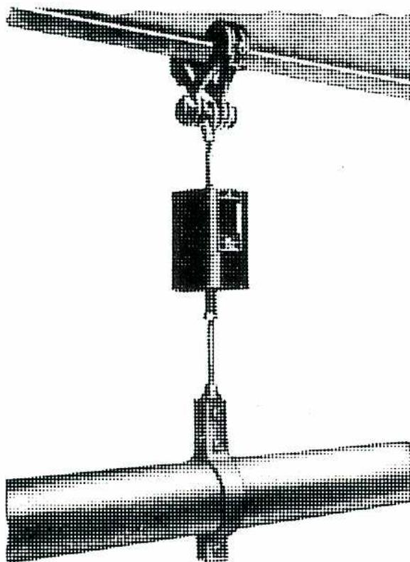A technical drawing of a variable spring hanger. It consists of a top horizontal beam, a vertical rod, a central spring housing, and a bottom horizontal beam. The top beam is connected to the vertical rod via a bracket and a spring mechanism. The bottom beam is connected to the vertical rod via a bracket and a spring mechanism. The central spring housing contains a coiled helical spring.
