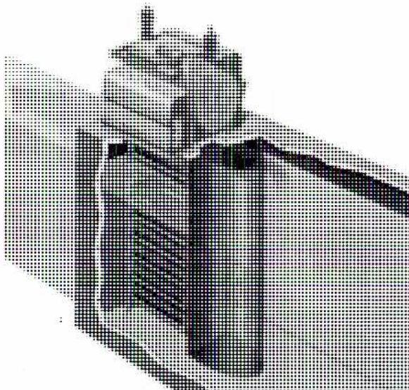 A black and white photograph of a Travelling Screen Dual-Flow (US Filter) unit. This unit appears more complex than the one in Figure 25, with additional piping and structural elements visible. It has a similar curved, ribbed main body but with more intricate connections at the top and sides.