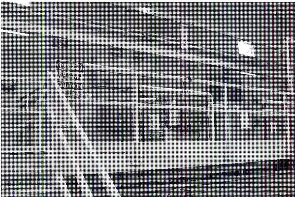 A black and white photograph showing a row of several large, rectangular chemical cleaning tanks in an industrial setting. The tanks are arranged in a line, and various pipes and hoses are connected to them. A sign on the left side of the tanks reads 'DANGER HAZARDOUS CHEMICALS KEEP OUT'.