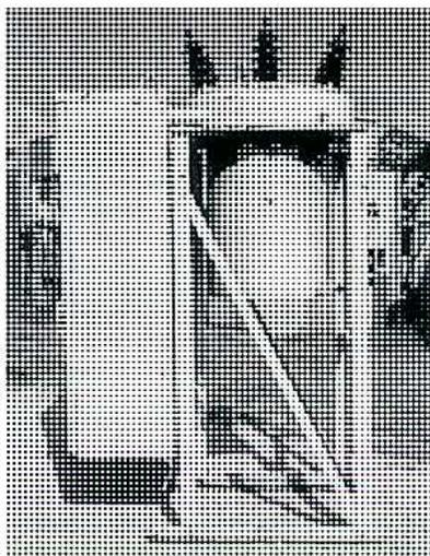Figure 15: Minimum Oil Circuit Breaker. This is a black and white photograph of a minimum oil circuit breaker. The device is shown within a dark, rectangular metal enclosure. The front of the enclosure has a large, square-shaped opening or window, through which internal components are partially visible. The overall appearance is more compact than the bulk oil breaker in Figure 14.