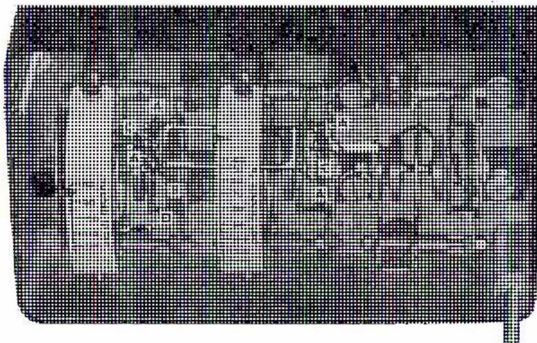 A black and white photograph showing the internal mechanism of a thermal overload relay. It features a complex assembly of metal parts, including a prominent spiral-shaped bimetallic element on the right side, various levers, and adjustment screws. The entire mechanism is housed within a dark, rectangular casing.