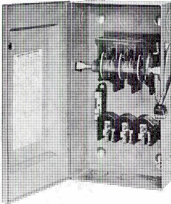 A photograph of a three-pole safety switch. The device is a rectangular metal box with a handle on the left side. The handle is in the 'OFF' position, pointing downwards. On the right side of the box, there are three vertical bars or lugs that are part of the internal switching mechanism. The box has a textured, metallic finish.